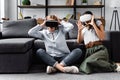 Friends with virtual reality headsets sitting on floor in apartment