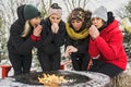 friends in winter coats sitting fire in forest