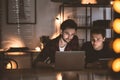 Friends working at the computer at night surrounded by lights