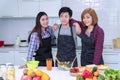 Friendship concept. Group friends standing in kitchen with table learning cook healthy food together. Enjoying young man and