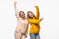 friendship, people and appiness concept. Two happy dancing girls on white background
