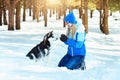 Young woman in winter snowy forest walking with her dog in a winter day. Friendship pet and human. Royalty Free Stock Photo