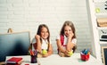 Friendship of small sisters in classroom at knowledge day. Happy school kids at lesson in september 1. Little girls eat Royalty Free Stock Photo