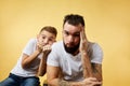Frighetened boy and father bite nails and look camera on yellow background Royalty Free Stock Photo