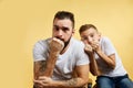 Frighetened boy and father bite nails and look camera on yellow background Royalty Free Stock Photo