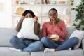 Frightened black girlfriends watching horror together at home