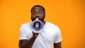Frightened black man screaming in megaphone, spreading information, awareness Royalty Free Stock Photo