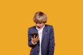 A frightened blond boy with a frightened face looks into his phone.