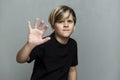 A frightened boy in a black T-shirt. Loneliness, stress and fear. Grey background