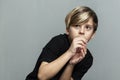 A frightened boy in a black T-shirt. Loneliness, stress and fear. Grey background