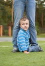 Frightened boy sits at feet of adult