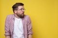 Frightened Caucasian man wearing glasses and casual clothes looks anxiously to the side. Copy space. Yellow background. Royalty Free Stock Photo