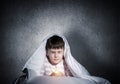 Frightened child with flashlight under blanket Royalty Free Stock Photo