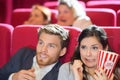 Frightened couple watching film in cinema