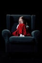 Frightened, depressed child sitting in armchair and covering eyes with hands