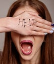 Help me Psychological portrait of woman`s cries for help with painted inscription on her hand. Fear, pain, depression