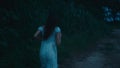 A frightened girl in a bloodstained dress runs away from her pursuer through the woods