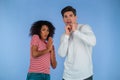 Frightened interracial couple afraid of something and looks into camera with big eyes full of horror on blue wall Royalty Free Stock Photo