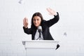 frightened lecturer suffering from glossophobia gesturing with hands while standing on podium tribune.