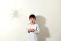 Frightened little girl wearing white casual shirt posing again]st gray wall with shadow of spider, female kid looking at camera Royalty Free Stock Photo