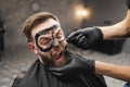 Frightened man grimaces while removing black facail skin mask in beauty salon Royalty Free Stock Photo