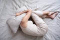 Frightened mature woman lying on bed fetal position covering pillow