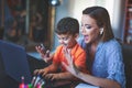 Frightened mother stopping little son typing on laptop in home office