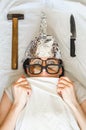 Frightened paranoid woman wears foil helmet and sleeps with weapon and different glasses because of mental illness