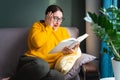 Shocked scared woman reading scary horror novel or thriller book at home