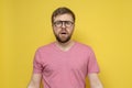 Frightened, shocked bearded man with glasses looks at the camera with large eyes and an open mouth. Yellow background. Royalty Free Stock Photo