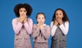 Frightened shocked international little girls in casual cover mouths with hands