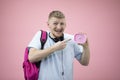 Excited student holds alarm clock in hands and points to dial. Late for meeting