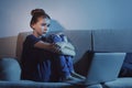 Frightened teenage girl with laptop on sofa. Danger of internet Royalty Free Stock Photo