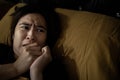 Frightened woman is looking around while lying on her bed,feeling anxious,afraid of shaking,hearing something haunting,symptoms of Royalty Free Stock Photo