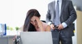 Frightened woman sits at computer in background businessman unfastens his belt Royalty Free Stock Photo