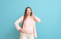 Frightened young pregnant woman on blue background calls by mobile phone, discharge of amniotic fluid, the beginning of labor