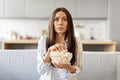 Frightened young woman watching scary movie at home and eating popcorn Royalty Free Stock Photo