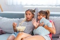 Frightened young women watching movie at home. Girls watching a terror movie on tv sitting on a couch at home Royalty Free Stock Photo
