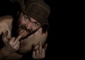 Frightening bearded man showing middle finger. strange Russian man with a naked torso and a woolen hat. free space for