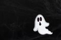 A frightening white ghost flies on a black background with a web, a Halloween postcard