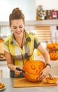 Happy housewife carving a big orange pumpkin Jack-O-Lantern Royalty Free Stock Photo