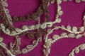 Fringe of a warm beige woolen scarf on a lilac-burgundy background