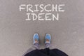 Frische Ideen, German text for Fresh Ideas text on asphalt ground, feet and shoes on floor Royalty Free Stock Photo