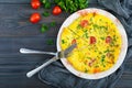 Frittata. Italian omelette with cheese, greens and tomatoes on a white plate on a wooden background. Royalty Free Stock Photo