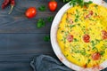 Frittata. Italian omelette with cheese, greens and tomatoes on a white plate on a wooden background. Royalty Free Stock Photo