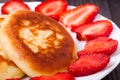 Fritters on a plate with strawberries wooden background