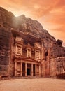 Front of Al-Khazneh Treasury temple carved in stone wall - main attraction in Lost city of Petra, orange sunset sky above Royalty Free Stock Photo