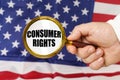 In front of the American flag, a man holds a magnifying glass in his hand with the inscription - CONSUMER RIGHTS