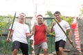 Front angle of three young men in red and white attributes with raised fist and hold spiky bamboo