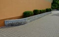 In front of the apartment building is a raised flower bed with a brick wall. trimmed evergreen bushes in the shape of balls or bou Royalty Free Stock Photo